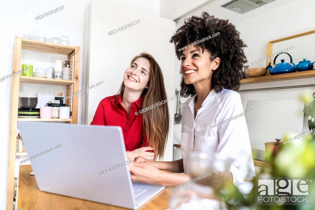 Stock Photo: Two women working together in kitchen, using laptop.