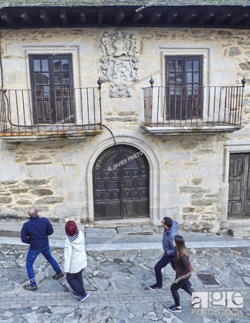 Stock Photo: Four visitors on a walk through Puebla de Sanabria pass by a manor house with noble coat of arms on a street in Puebla de Sanabria. Zamora.