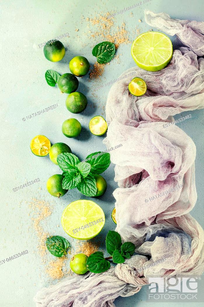 Stock Photo: Ingredients for mojito cocktail, whole, sliced lime and mini limes, mint leaves, brown crystal sugar over gray stone texture background with gauze textile.