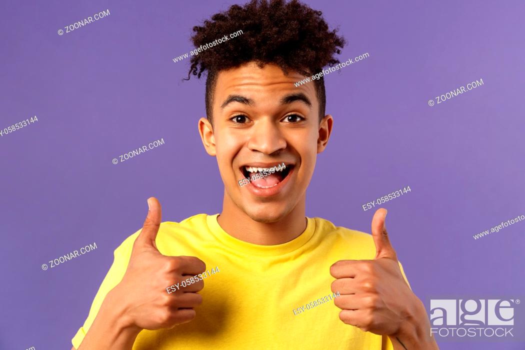 Stock Photo: Close-up portrait of enthusiastic, lively hipster guy with afro haircut agree with something, show thumbs-up smiling with joy, recommend good product.