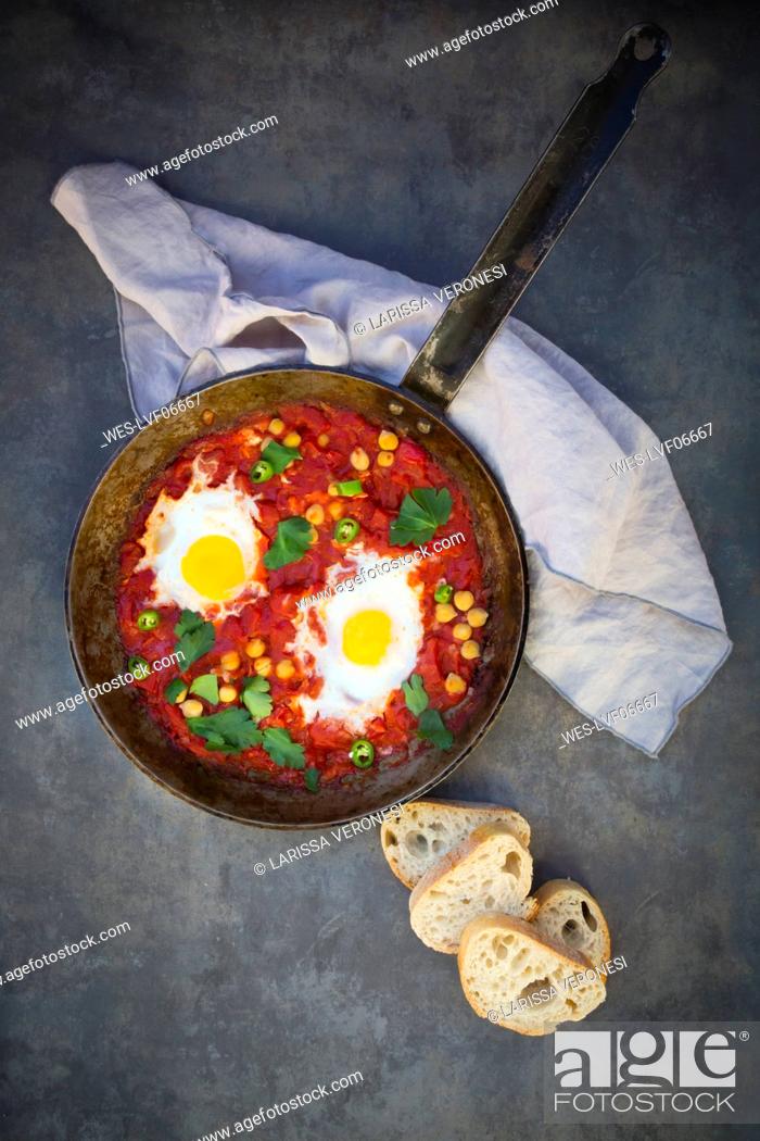 Stock Photo: Shakshouka with chick peas in pan and slices of baguette.