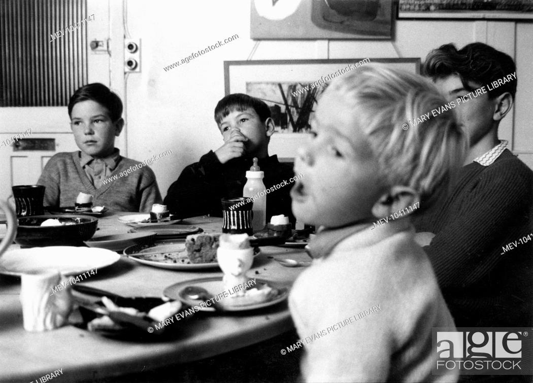 Stock Photo: Four boys sit round a table, having had a nice tea, which has included boiled eggs and fruit cake. There is also a baby's bottle, but no sign of the baby.