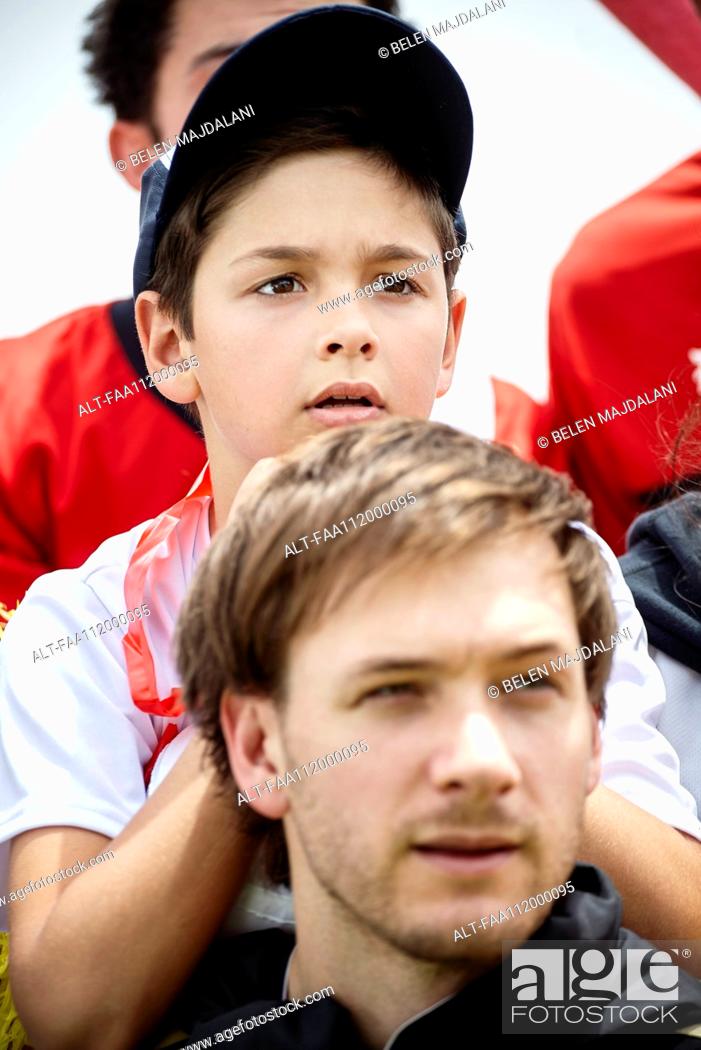 Stock Photo: Father and son watching football match together.