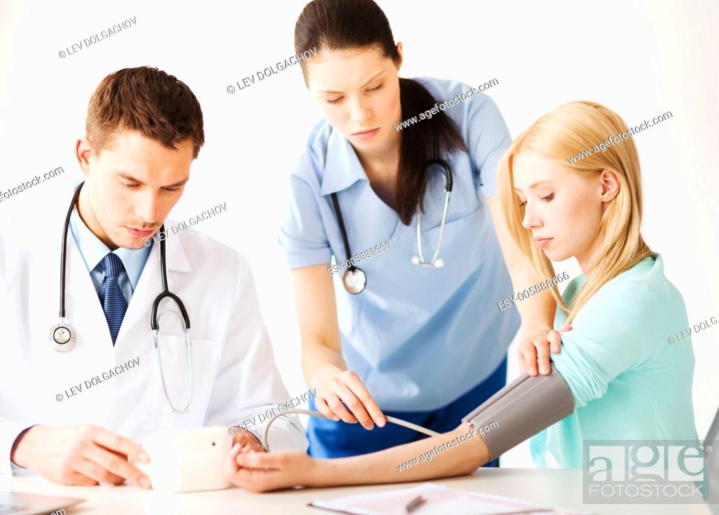 Photo de stock: healthcare and medical concept - doctor and nurse with patient measuring blood pressure in hospital.