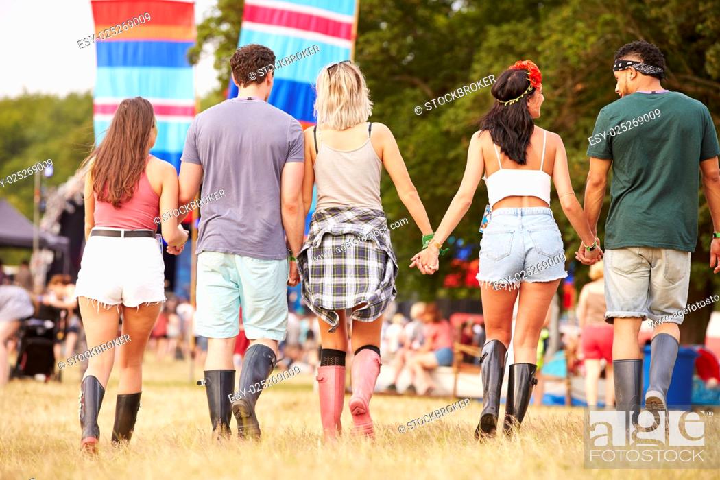 Stock Photo: Friends walking together at a music festival site, back view.