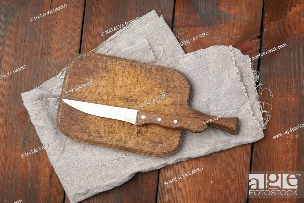 Stock Photo: very old empty wooden rectangular cutting board and knife, top view, brown wooden background.