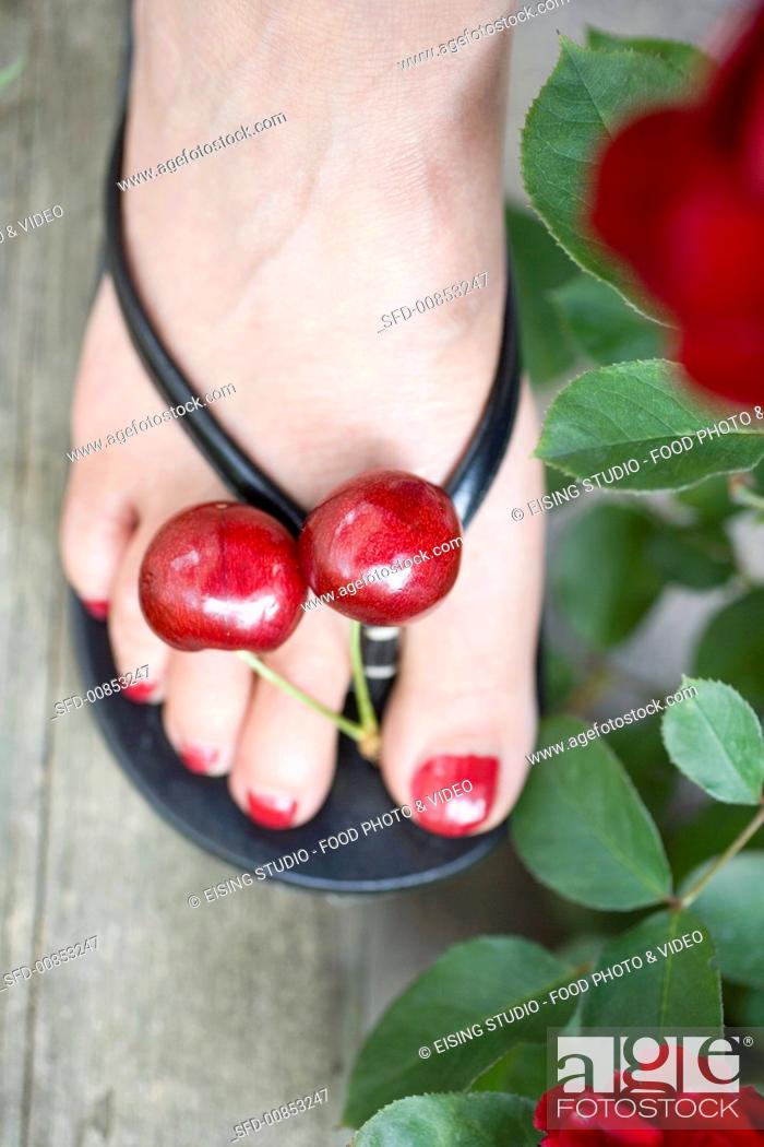 Stock Photo: A pair of red cherries between someone's toes (overhead view).