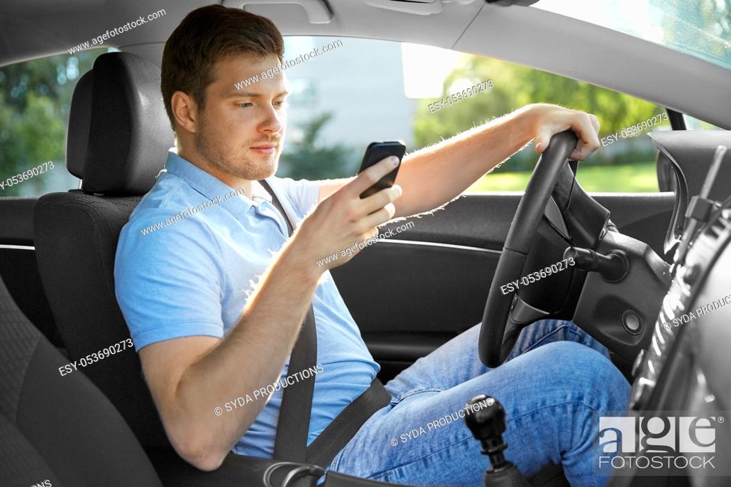 Stock Photo: man driving car and using smartphone.