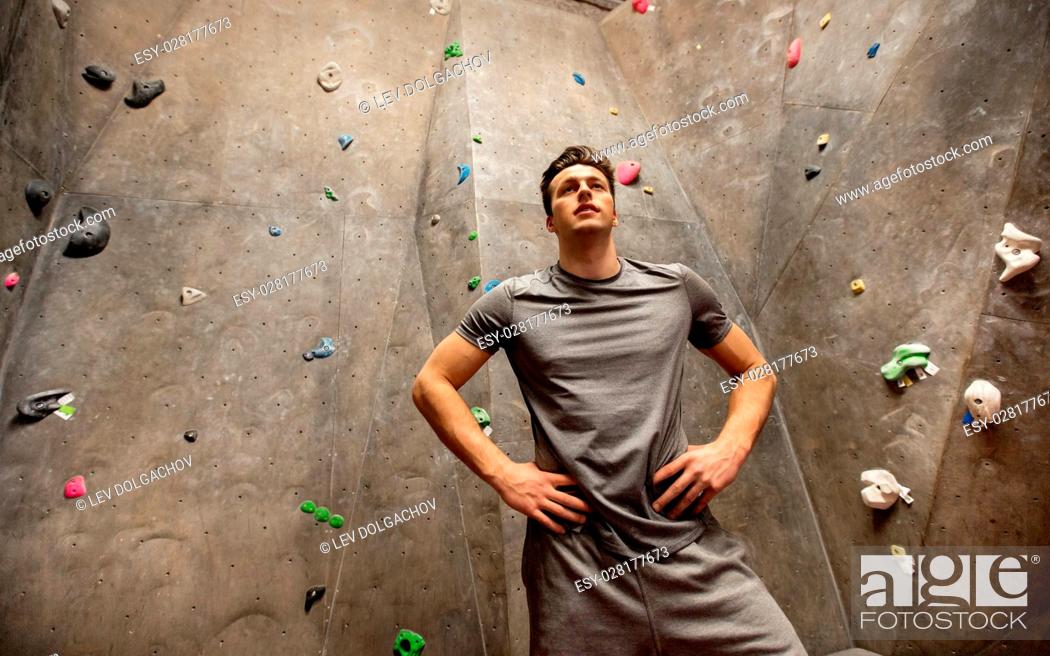 Stock Photo: fitness, extreme sport, bouldering, people and healthy lifestyle concept - young man exercising at indoor climbing gym.