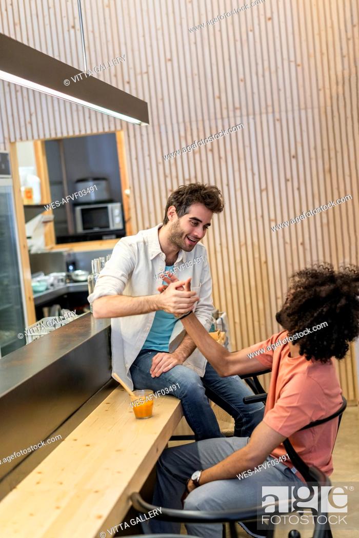 Stock Photo: Two men dhaking hands in a bar.