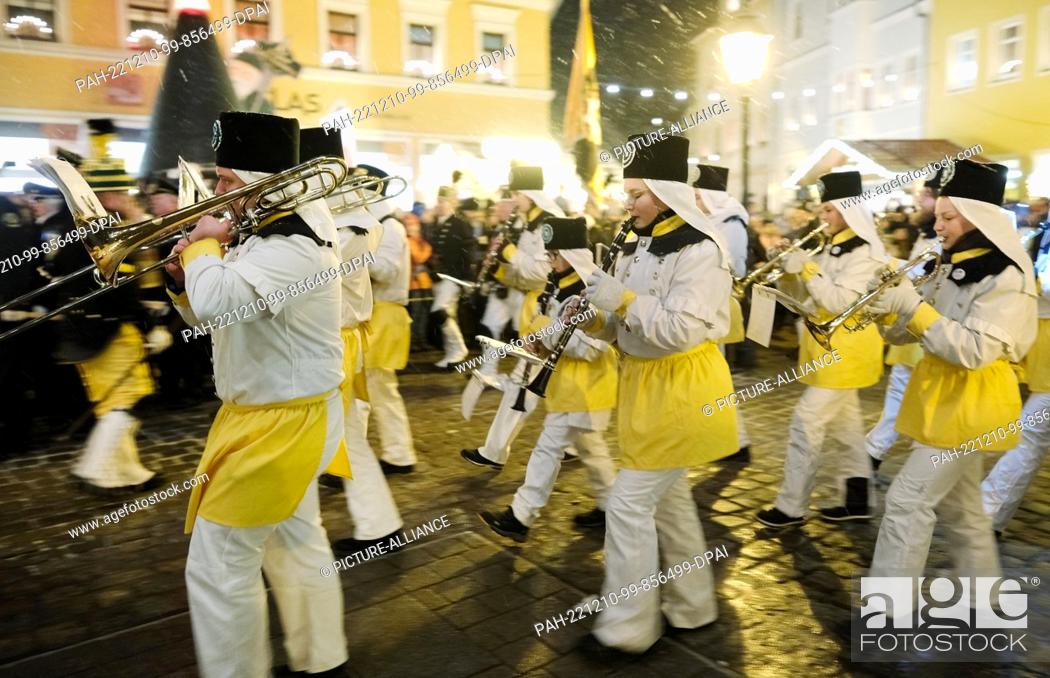 Stock Photo: 10 December 2022, Saxony, Oberwiesenthal: Actors from miners' clubs march with music to the market square. A traditional mining parade took place there.