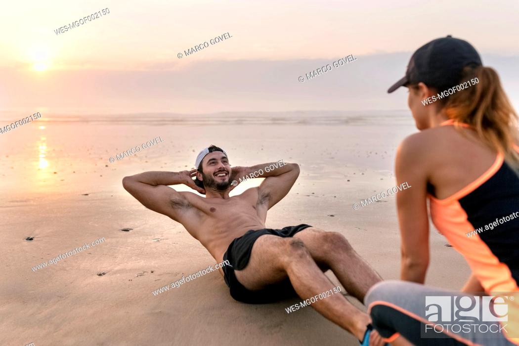 Photo de stock: Athletes couple training on the beach at sunset.