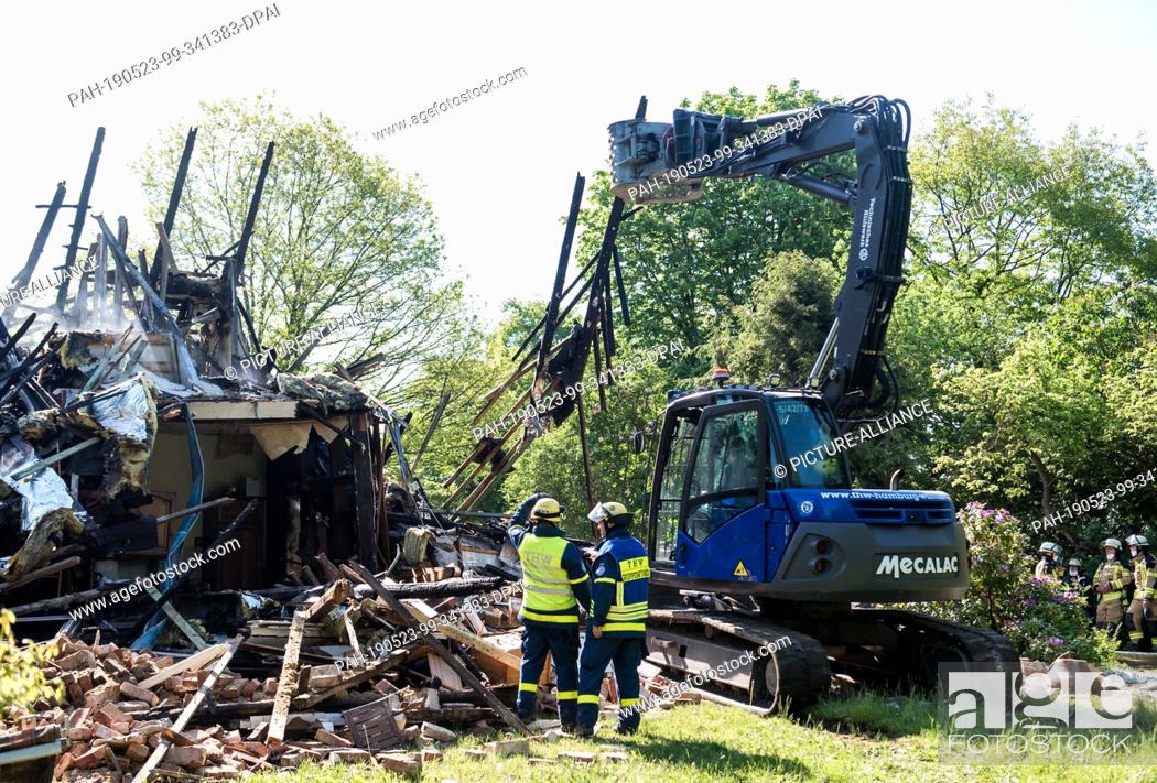Stock Photo: 23 May 2019, Schleswig-Holstein, Wohltorf: An excavator from the German Federal Agency for Technical Relief is pulling apart rubble from a house that was.