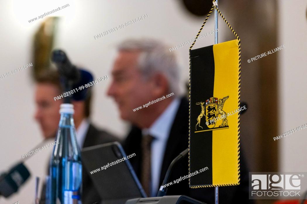 Stock Photo: 11 October 2022, Baden-Württemberg, Freiburg: The flag of Baden-Württemberg stands on a table while Thomas Strobl (CDU), Minister of the Interior of.