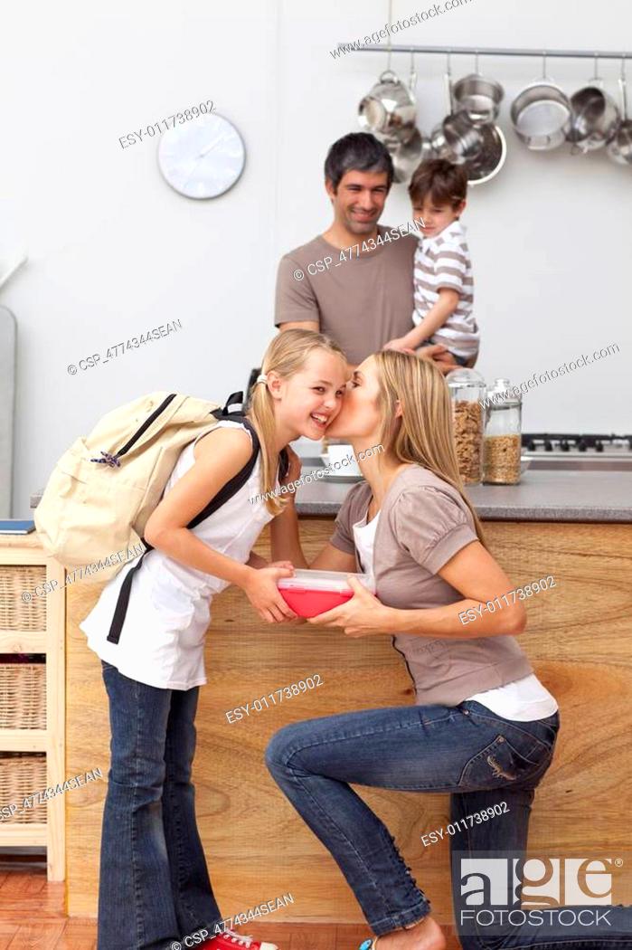 Stock Photo: Mother giving her daughter the school lunch and a kiss.