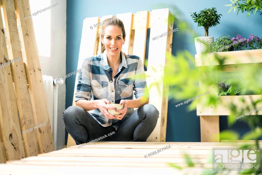 Stock Photo: Beautiful woman taking a break from refurbishing her home with pallets, drinking coffee.