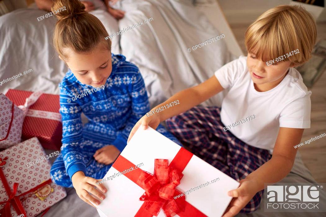 Stock Photo: Kids opening big Christmas gift in the bed.