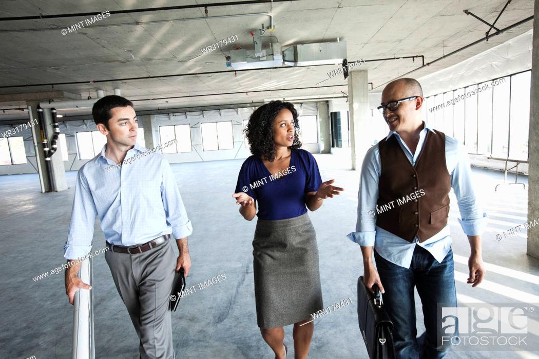 Stock Photo: Mixed race team of business people touring a new empty raw office space.