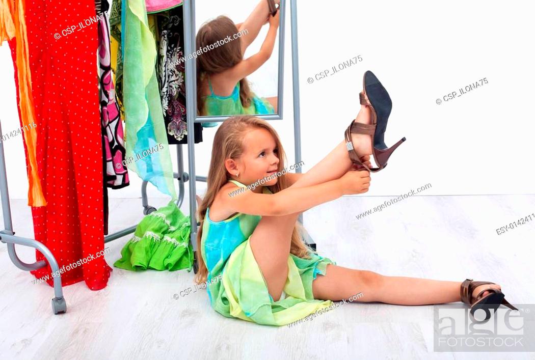 Stock Photo: Little girl trying her mother's shoes and clothes.