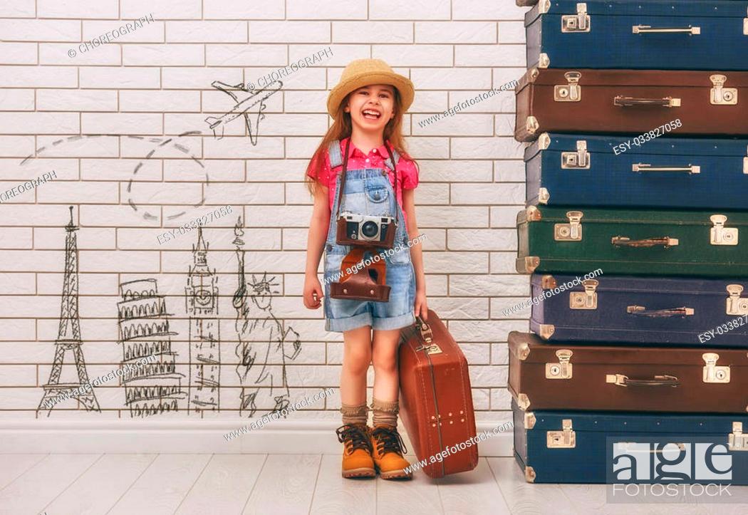 Stock Photo: happy child girl against a white brick wall. girl having suitcases and dreaming of traveling.