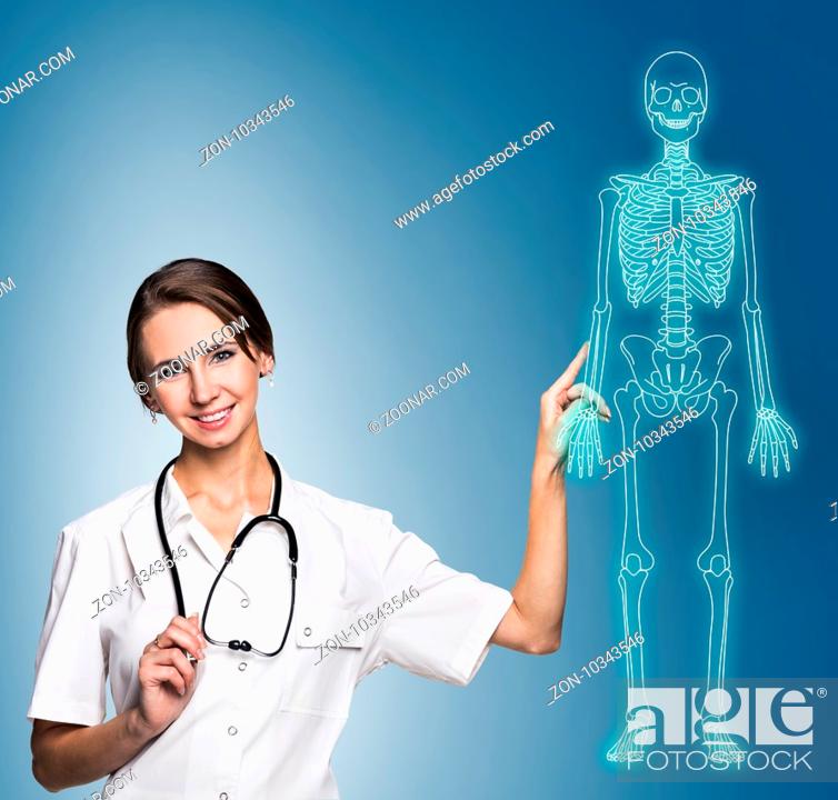 Stock Photo: Medical doctor woman pointing on drawing human skeleton, over blue background.