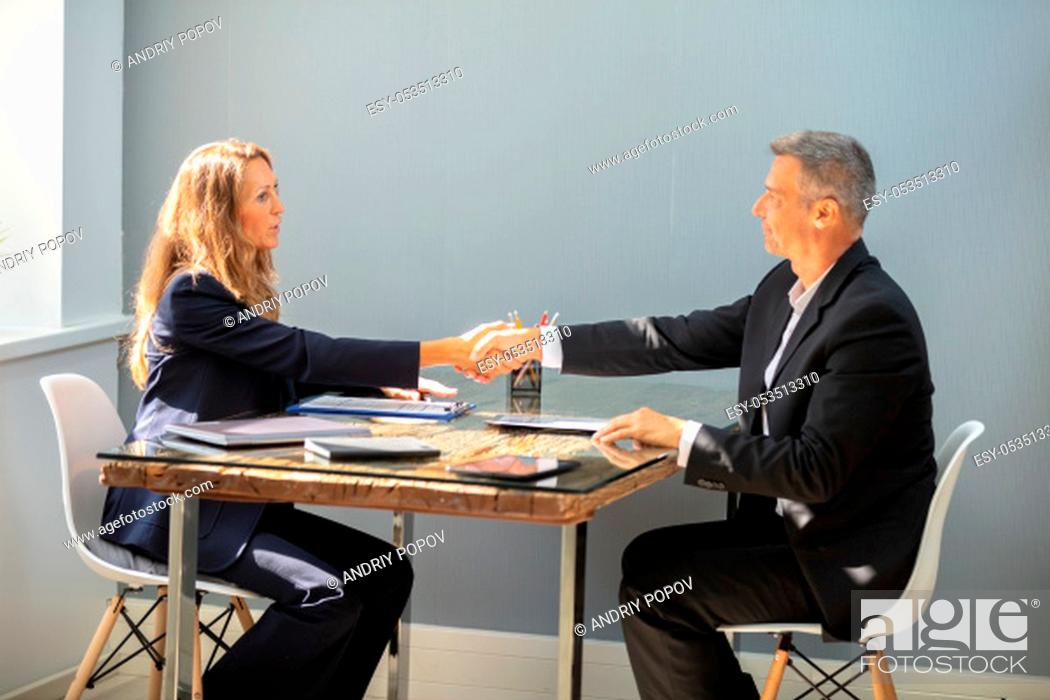 Stock Photo: Smiling Mature Businessman Shaking Hand With Female Candidate Over Desk At Workplace.