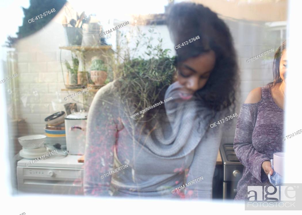 Photo de stock: Mother and daughter at kitchen window.