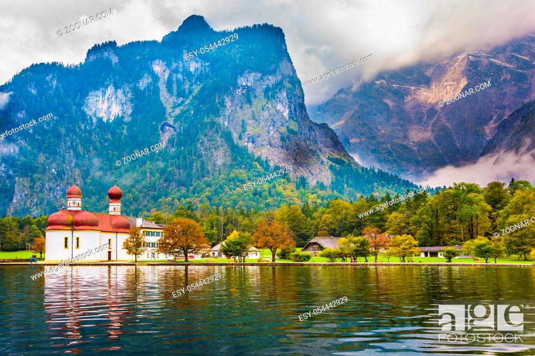 Stock Photo: The lake Königssee is surrounded by high mountains. he picturesque church of St. Bartholomew with bright red domes. The concept of active.