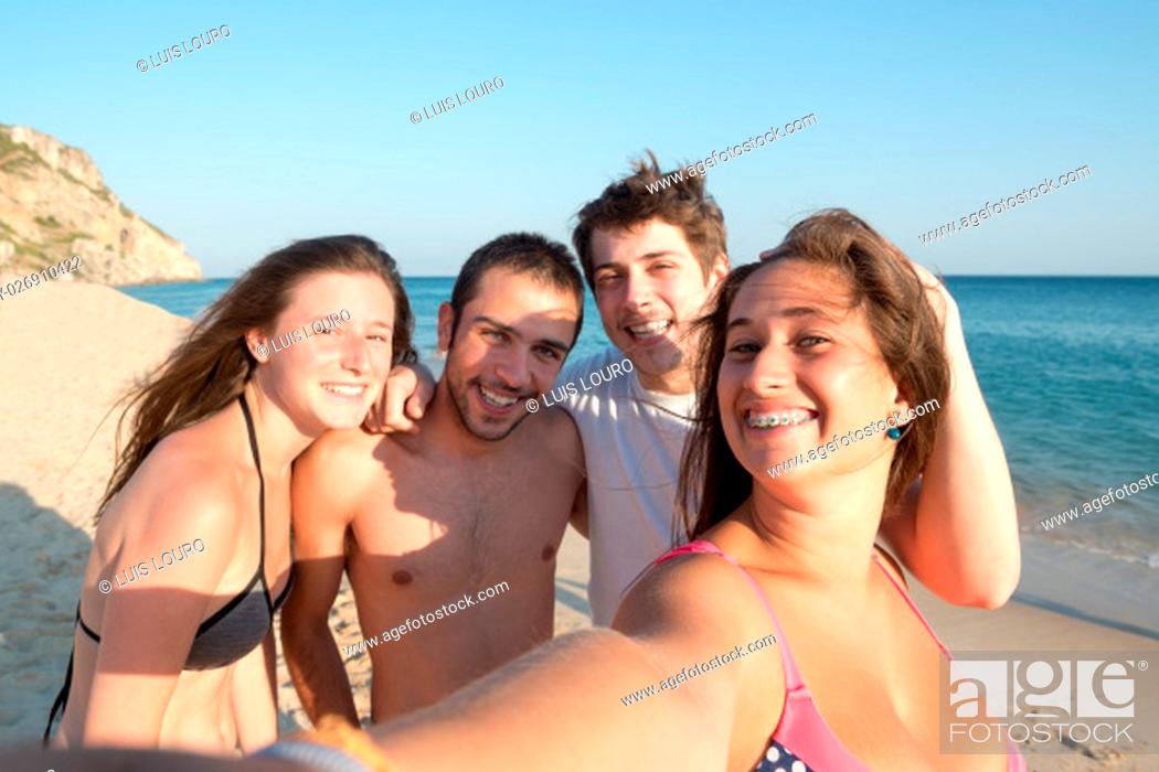 Stock Photo: Group of happy teenage friends taking a selfie in the beach.
