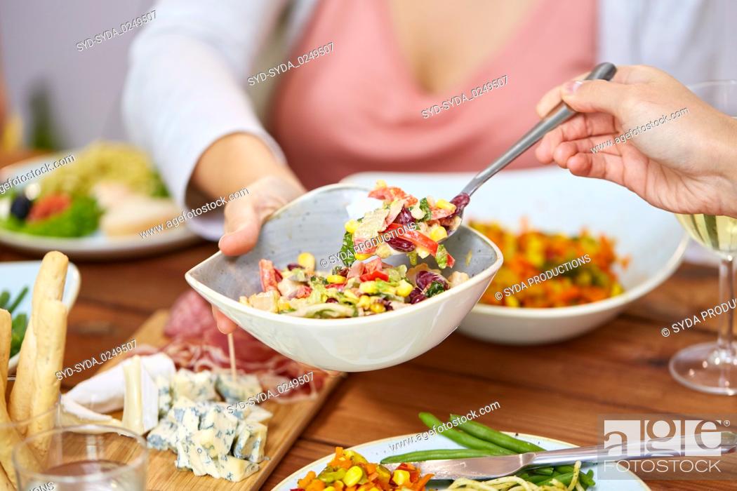 Stock Photo: people eating salad at table with food.