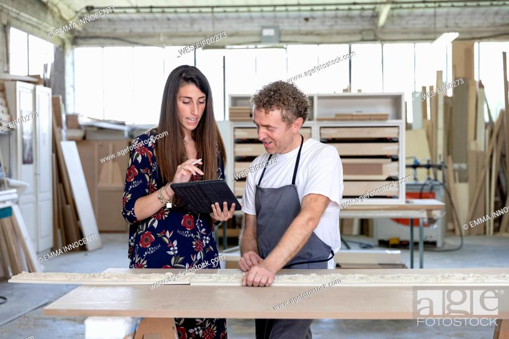 Stock Photo: Interior designer showing digital tablet to carpenter while standing at workshop.