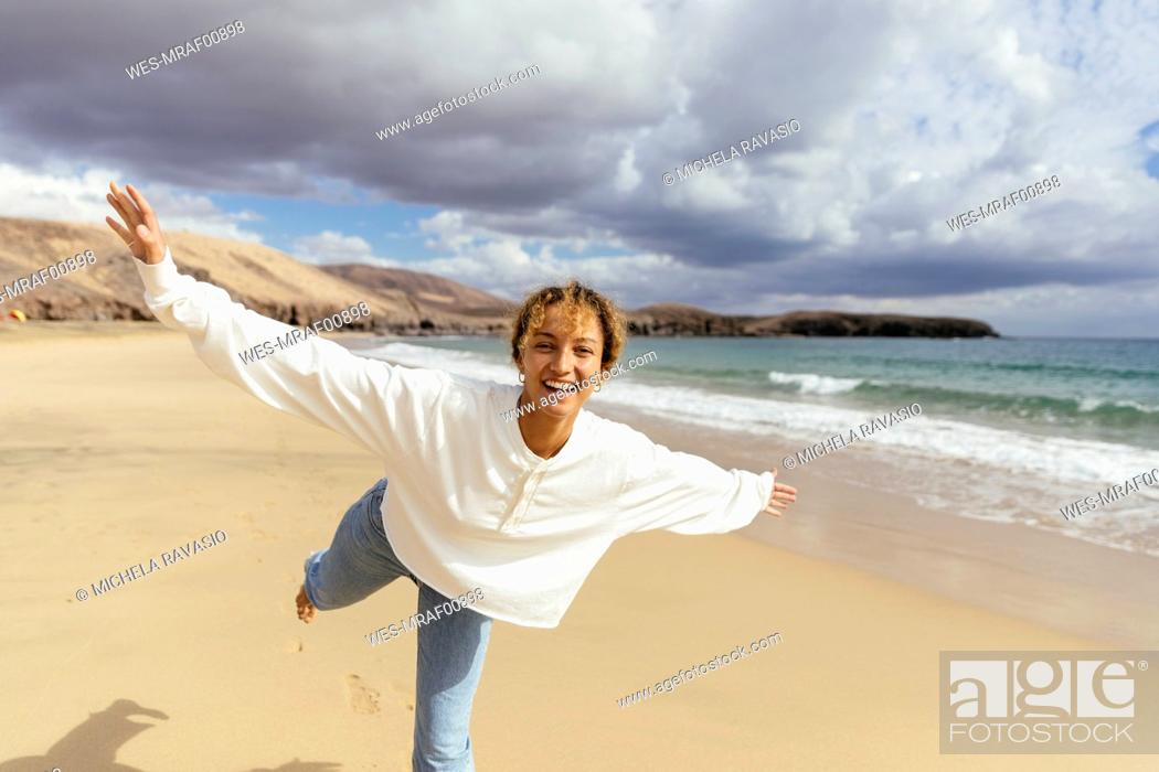 Stock Photo: Happy woman with arms outstretched enjoying at beach on sunny day.