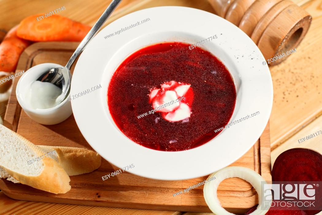 Stock Photo: Ukrainian and Russian traditional beetroot soup - borscht in clay pot with sour cream, spice, garlic, pepper, dried herbs and bread on dark wooden background.