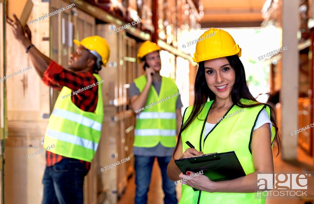 Stock Photo: Portrait female white caucasian warehouse worker stand with clipboard and pen for inventory check with colleagues in large warehouse distribution background.