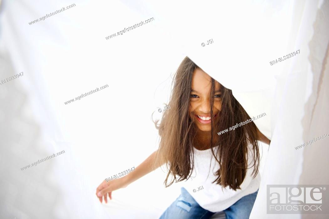 Stock Photo: Mixed Race girl playing with curtain.