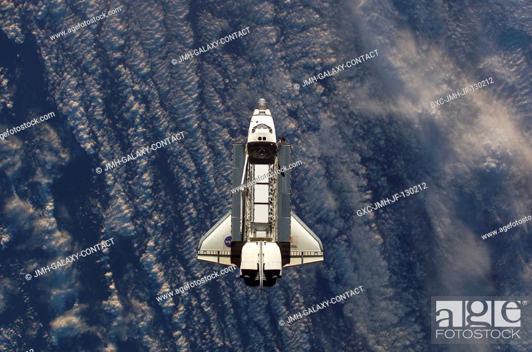 Stock Photo: Backdropped against a blue and white Earth, this view of the Space Shuttle Atlantis was photographed by an Expedition Five crewmember onboard the International.
