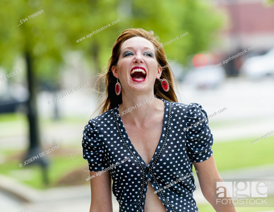 Stock Photo: Portrait of a happy 31 year old red headed woman in an urban setting wearing jeans and a mid drift top.