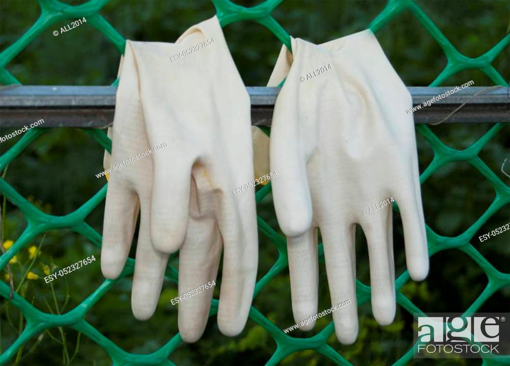 Photo de stock: A pair of protective gloves for working in the garden, turned inside out, dried on the grate.