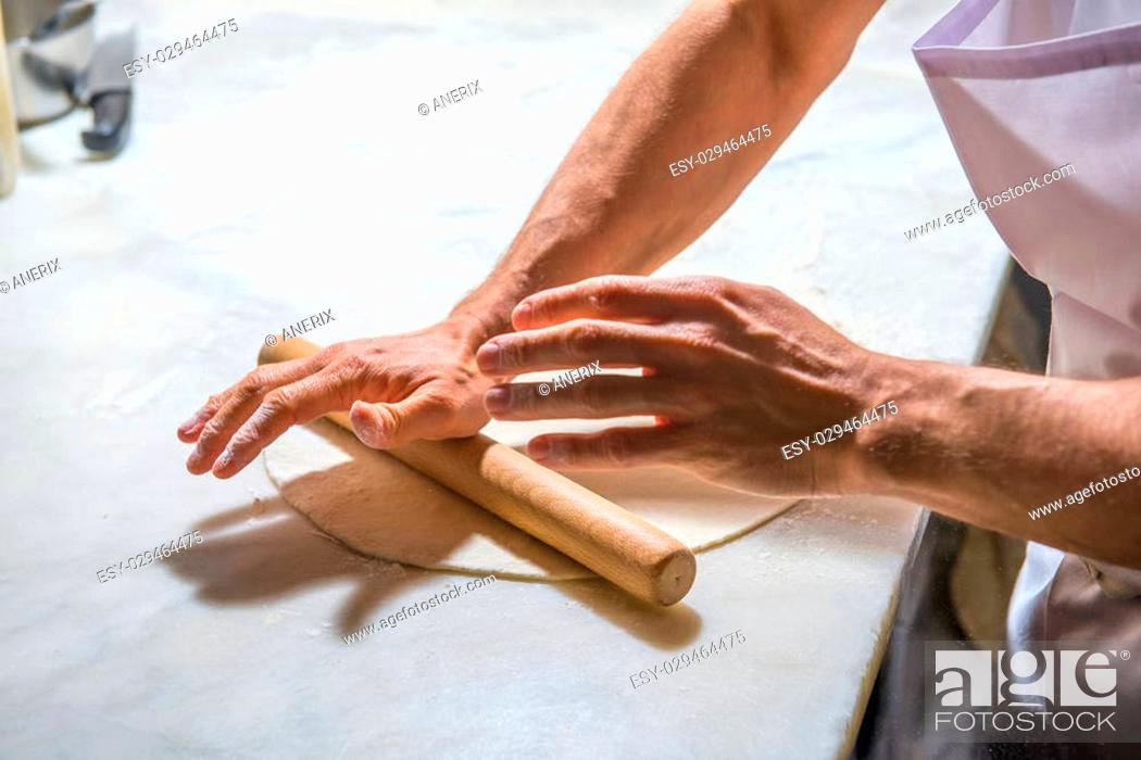 Stock Photo: Pizza chef spreading out and garnishing a delicious pizza.