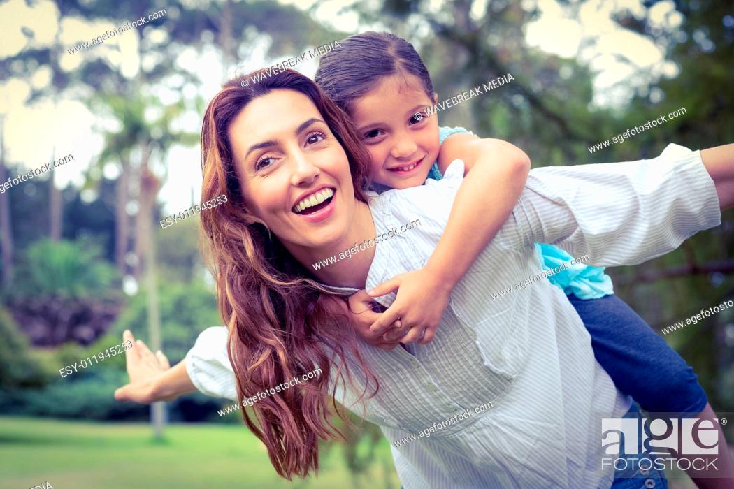 Stock Photo: Happy little girl getting a piggy back from mother in the park.