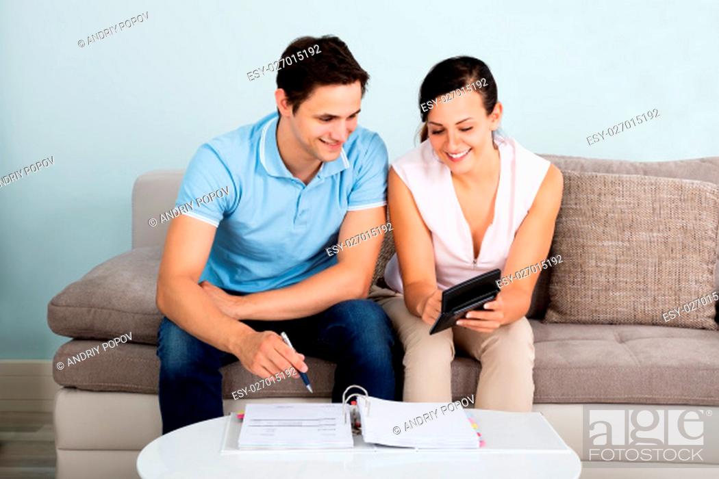 Stock Photo: Young Happy Couple Sitting On Sofa Calculating Budget At Home.