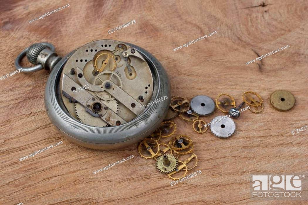 Stock Photo: broken vintage pocket watch on wooden background.