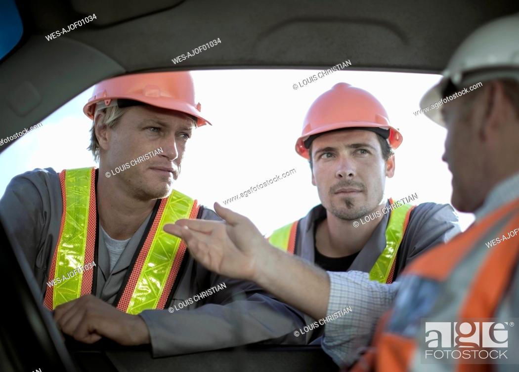 Imagen: Male architect explaining construction workers while sitting in truck.