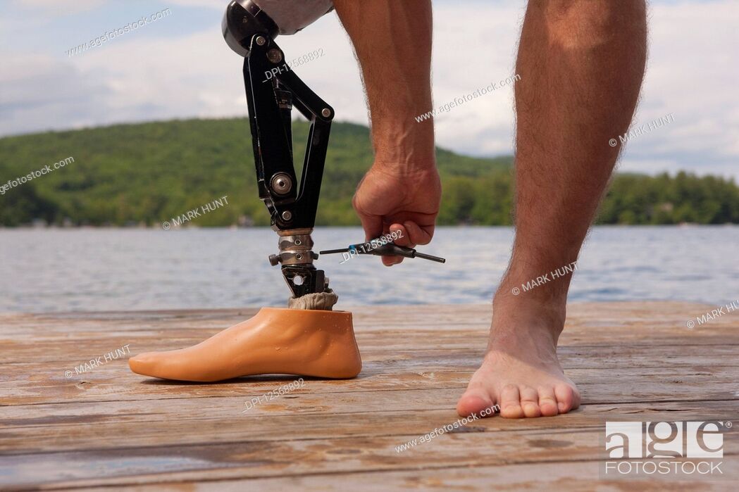 Stock Photo: Athlete adjusting his artificial leg on a dock.