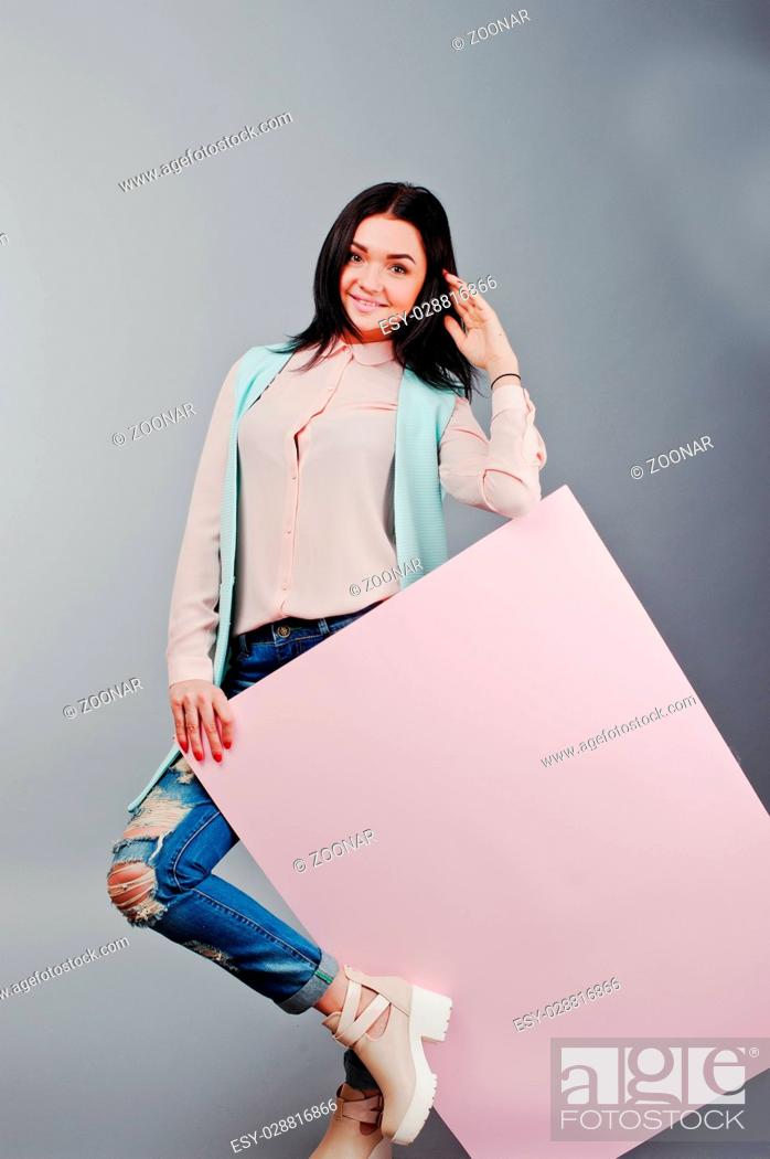 Imagen: Full length studio portrait of young girl model at ripped jeans and rose blouse with pink banner board.