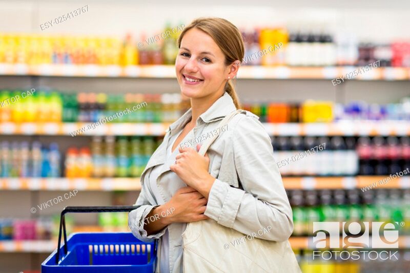 Stock Photo: Pretty, young woman with a shopping basket buying groceries in a supermarket/mall/gr ocery store (color toned image; shallow DOF).