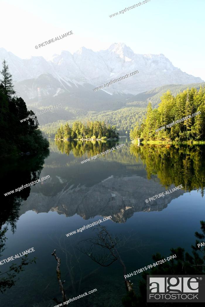 Stock Photo: 15 August 2021, Bavaria, Grainau: The Zugspitze (M) is reflected in the still smooth surface of the Eibsee. Photo: Angelika Warmuth/dpa.