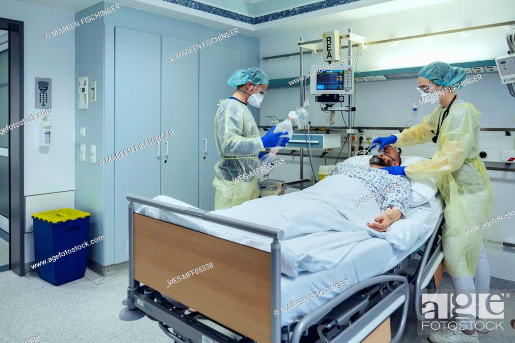 Stock Photo: Doctors caring for patient in emergency care unit of a hospital changing breathing from oxygen mask to bag valve mask.