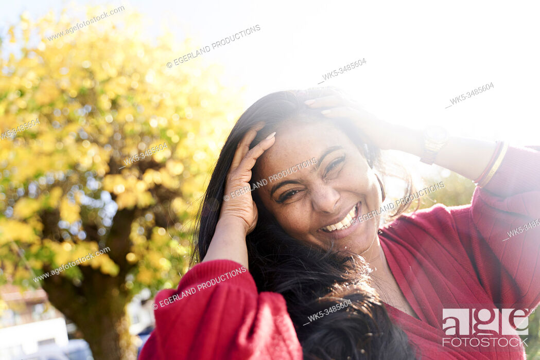 Imagen: happy mature Indian woman next to ageing tree, autumn season.