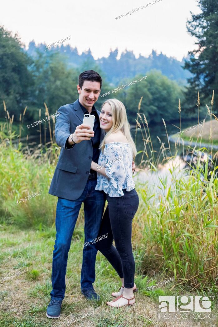 Stock Photo: A young couple taking a self-portrait with a smart phone; Bothell, Washington, United States of America.